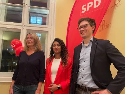 Roshani Thanapalasingham mit zwei weiteren Personen vor einem SPD-Banner