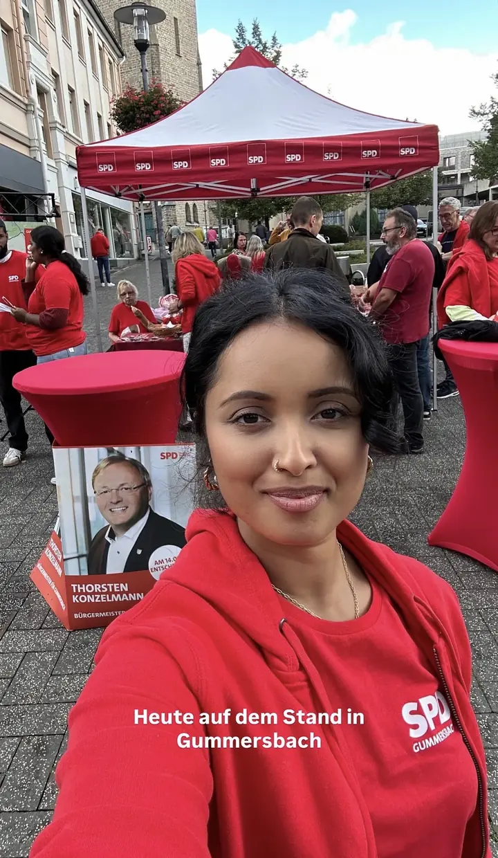 Roshani Thanapalasingham in rotem SPD-Pullover an einem SPD-Stand in Gummersbach